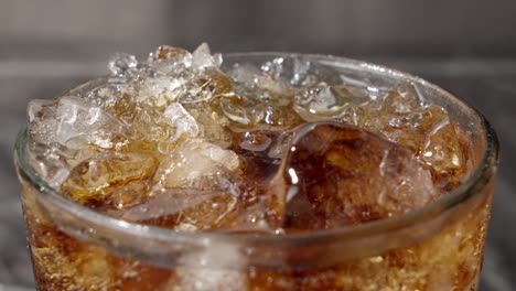 Frisches-Erfrischungsgetränk-In-Einem-Glas-Mit-Eis-Und-Blasen,-Nahaufnahme-Einer-Sprudelnden-Flüssigkeit