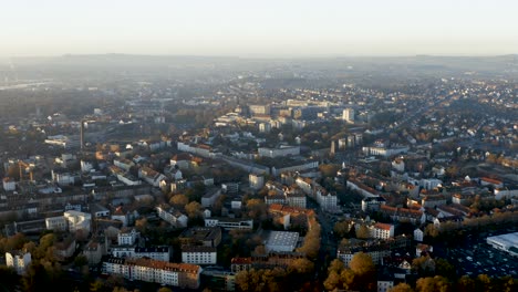 Drohnenaufnahme-Der-Stadtlandschaft-Von-Kassel-In-Schönem,-Weichem-Sonnenlicht-Und-Mit-Nebel-Bedeckt