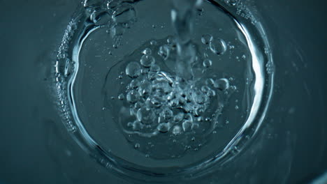 top view water pouring transparent cup closeup. diverse air bubbles flowing