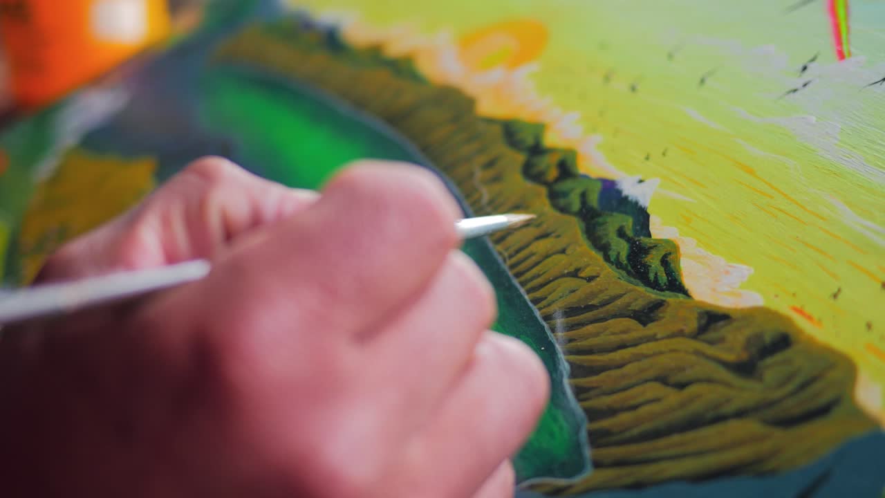 Close up shot of a painter's hand drawing art on a canvas
