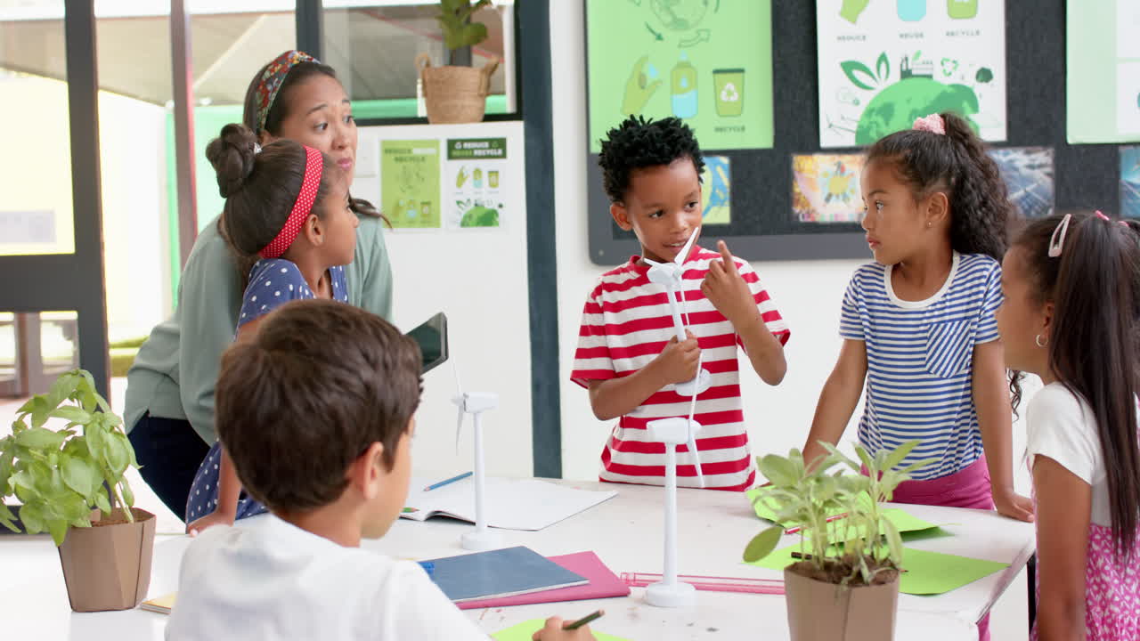 In school, teacher and students discussing science project with wind turbines