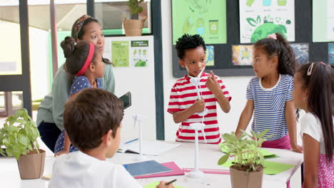 in school, teacher and students discussing science project with wind turbines