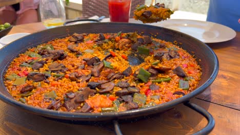 cubriendo con una cuchara grande plato tradicional español de paella con verduras en un restaurante, sabroso arroz cocido con verduras, marbella españa, 4k tiro