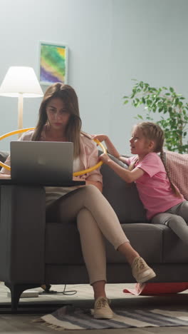 young woman works at home, little children distract her mother, do not allow her to work at computer
