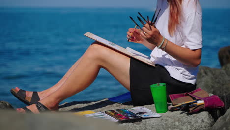 woman painting seascape on the beach