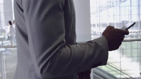 Businessman-using-mobile-phone-in-the-corridor-at-office-4k