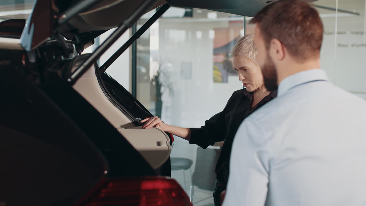 cliente y vendedor examinando un maletero de coche
