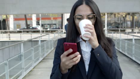 Mujer-De-Negocios-Con-Café-Para-Llevar-Usando-Un-Teléfono-Inteligente-En-La-Calle