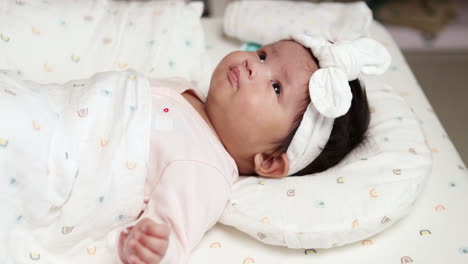 estirando sus piernas y brazos mientras se mueve de un lado a otro, un bebé recién nacido también le está frotando los ojos y mostrando una pequeña sonrisa en su rostro gordo