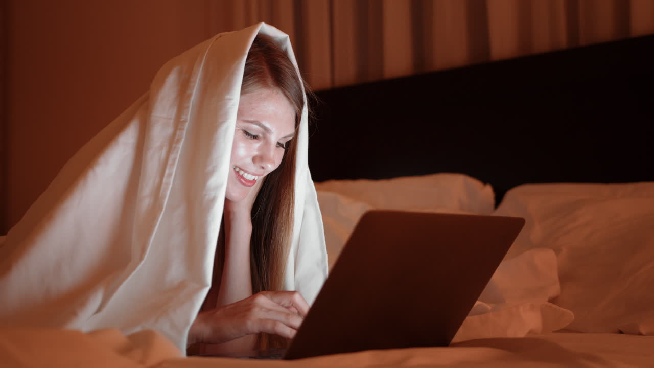mujer usando la computadora portátil en la cama por la noche