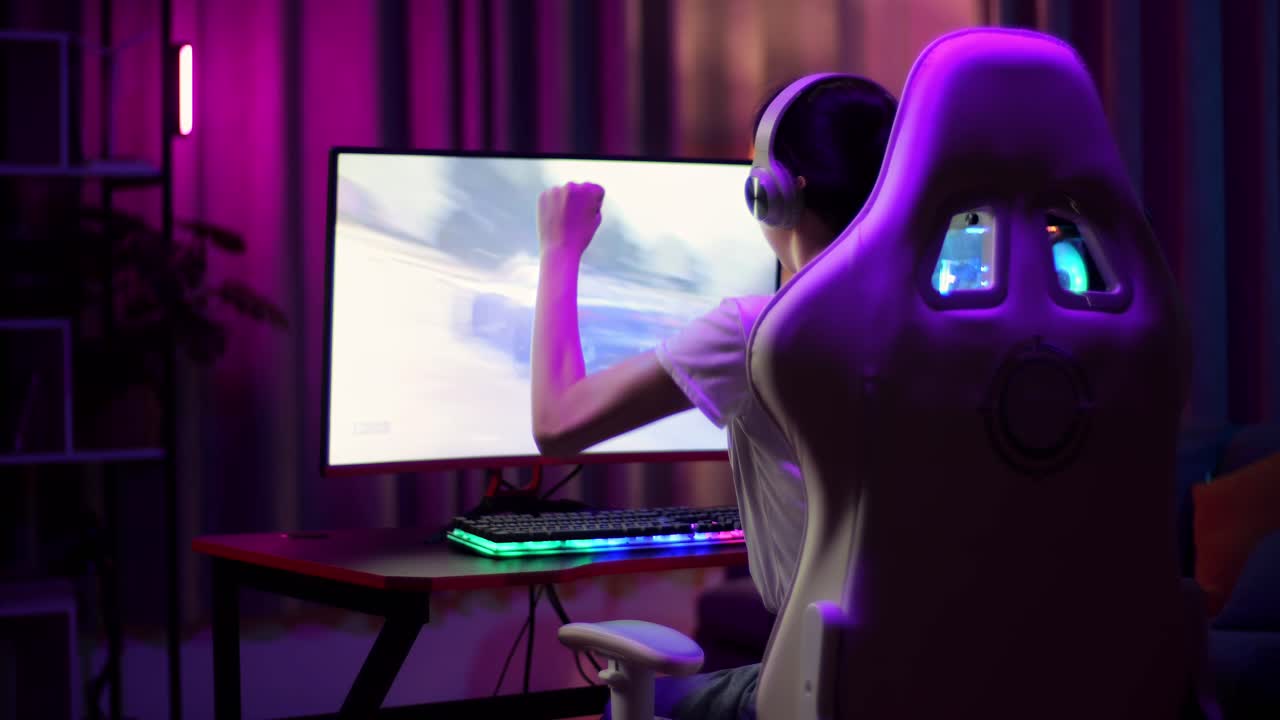 Adolescente asiatica gamer entusiasta festeggia la vittoria e balla mentre gioca a un videogioco al computer, giocando a un videogioco di corse
