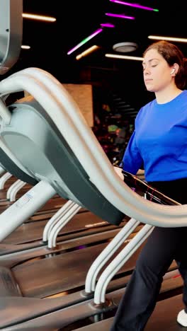 Young woman starting to walk on treadmill at gym