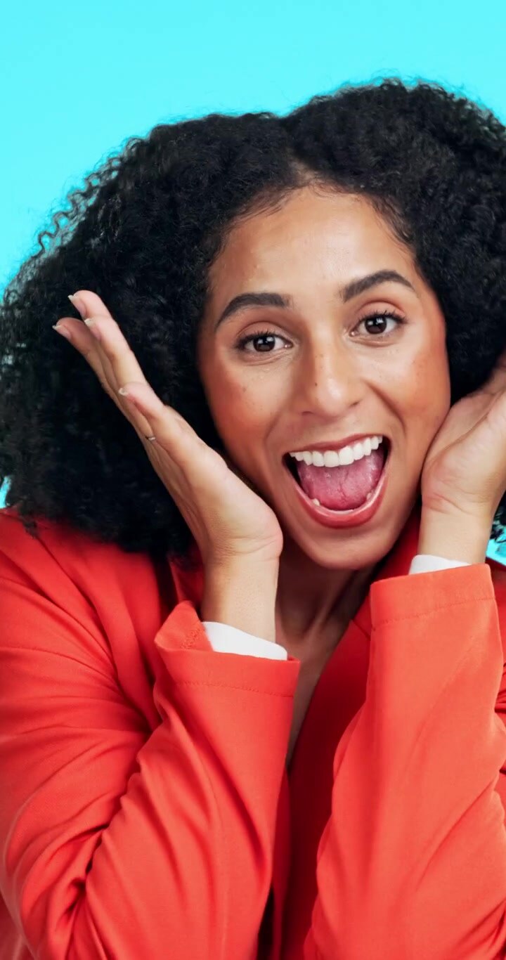 Excited Woman With Curly Hair Expressing Surprise Against Blue Background