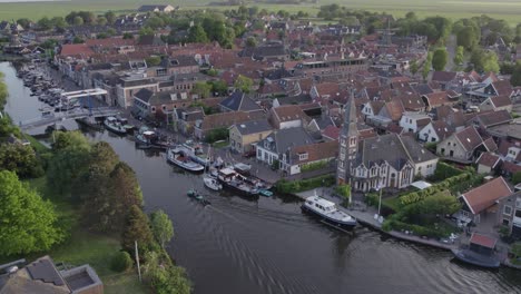 Vista-Aérea-Del-Pueblo-De-Woudsend-Con-Crucero-En-Barco-Durante-La-Puesta-De-Sol,-Drone