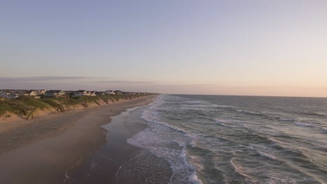 Tiro-De-Drone-De-Playa-Con-Olas-Rompiendo-Y-Luego-Subiendo-Para-Mostrar-Casas-En-La-Costa-En-Los-Bancos-Exteriores-De-Carolina-Del-Norte