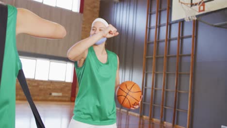 diverse female basketball team greeting with elbows, wearing face masks