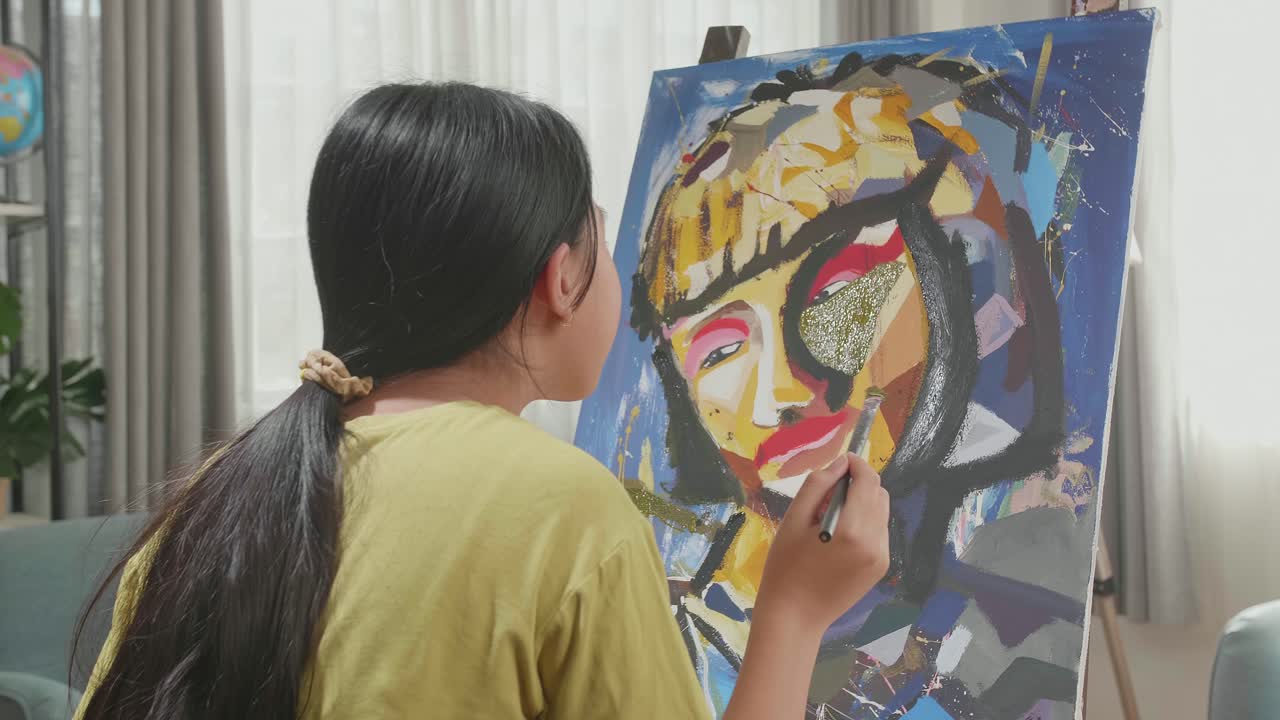 Hind View Of An Asian Artist Girl In Wheelchair Thinking And Painting A Girl'S Face On The Canvas