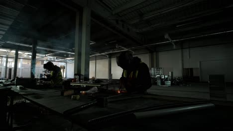 professional welders are working in the factory wearing safety equipment. metalwork manufacturing, industrial process.