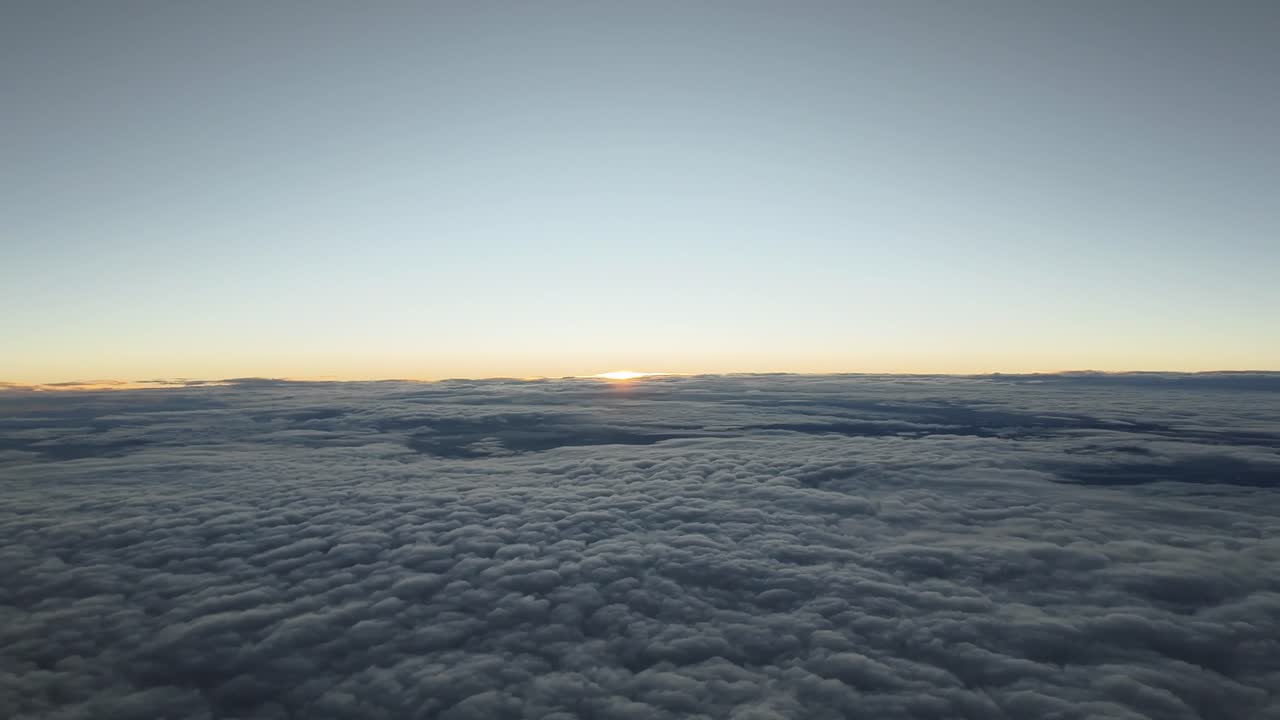 Aerial footage of a sunset taken from a jet cockpit while flying over a layer of clouds. Hyper lapse. 4K