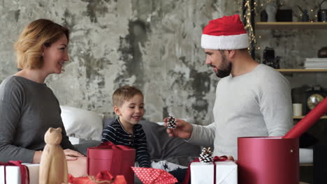 father playing with christmas decorations, doing magic trick, wearing red hat