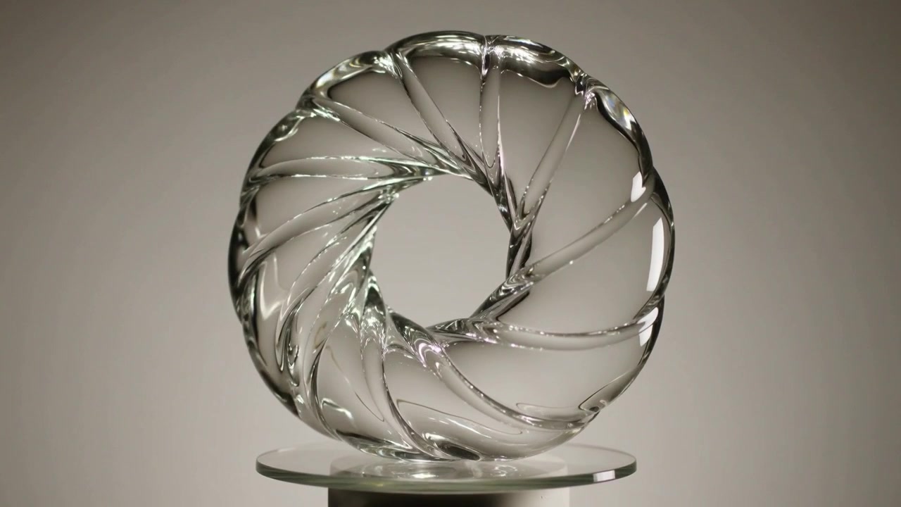 Spinning turntable motor turning clear glass torus on glass platter, revealing spiral highlights
