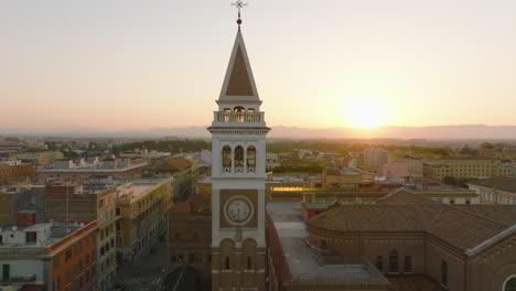 Orbit-shot-around-tower-at-sunrise.-Church,-buildings-in-urban-borough-and-distant-mountain-in-background.-Rome,-Italy