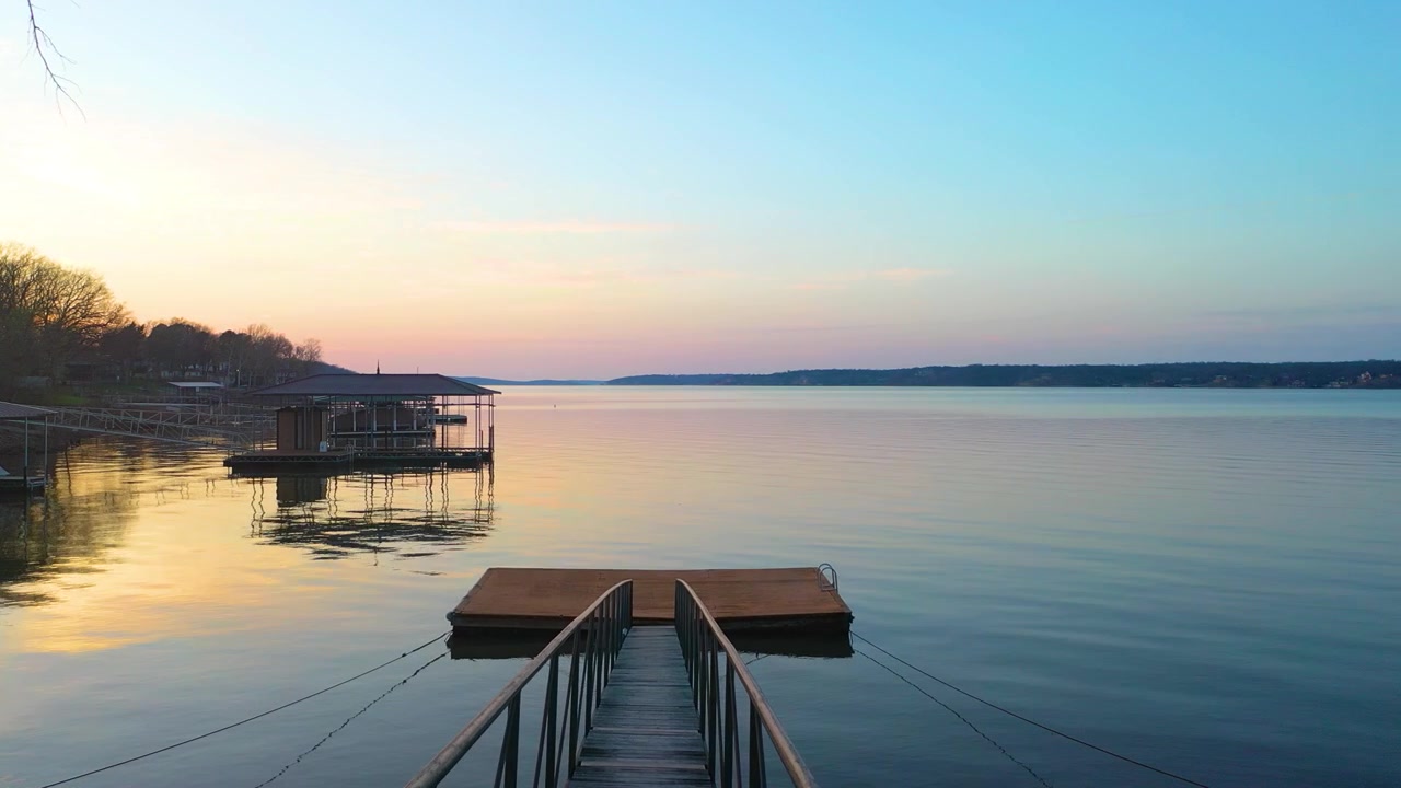 Ampia vista aerea del lago Table Rock in Missouri, che mostra moli tranquilli, case sul lago, rive alberate, luce pastello del tramonto e acque calme e aperte che si estendono verso l'orizzonte