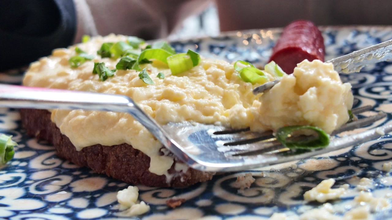 Person Eating Scrambled Eggs on Toast with Green Onions