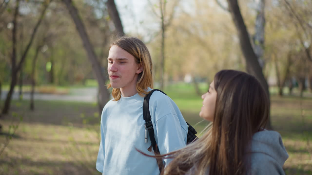 햇살이 비치는 나무 아래를 걷는 십 대들, 활기찬 봄날 공원 풍경 속에서 미소를 나누는 반 친구들, 밝은 햇빛과 푸르른 녹음 아래에서 즐거운 시간을 함께 보내는 어린 친구들