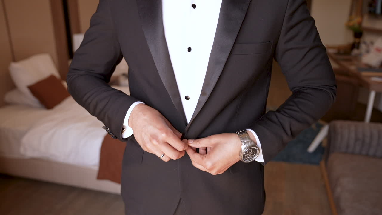 un novio sujeta su chaleco de traje y se prepara para la boda
