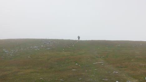 static shot of a hiker walking along ben chonzie under heavy fog