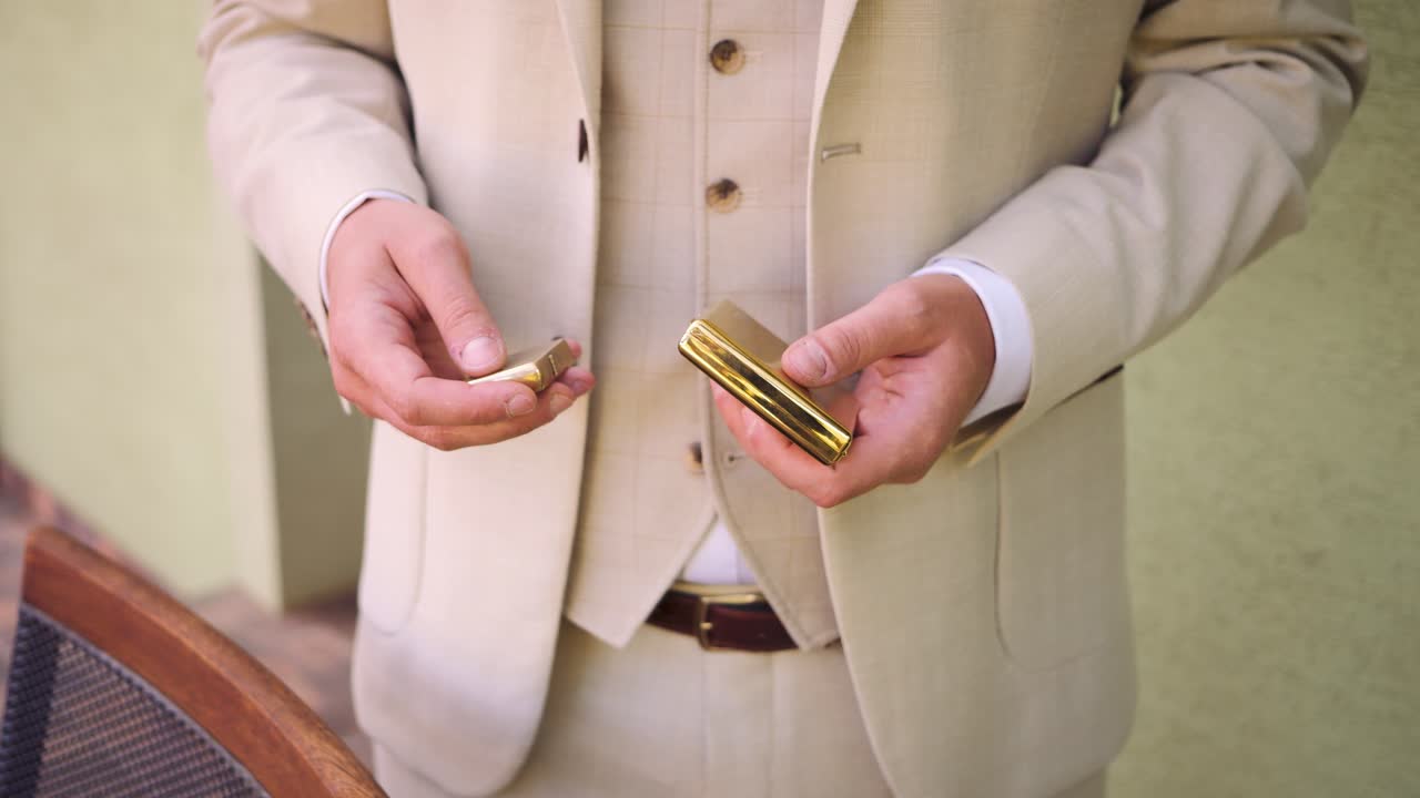 Elegant man in beige suit holding a vintage lighter outdoors