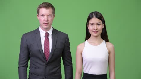 multi-ethnic business couple giving thumbs up together