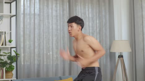 아시안 십대 소년 은 집 에서 셔츠 를 벗고 운동 하는 동안 장소 에서 뛰고 있다