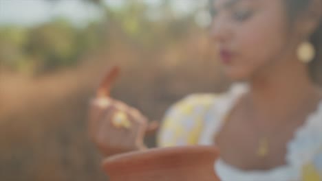 out of focus slow zoom in to delicate hand of young attractive indian woman holding a broken shard of pottery