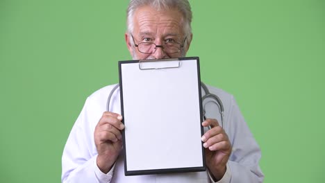 handsome senior bearded man doctor against green background