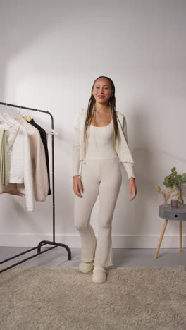 vídeo vertical de pov de una mujer influyente en las redes sociales produciendo contenido generado por el usuario en el estudio modelando una variedad de trajes de moda filmados en tiempo real 3