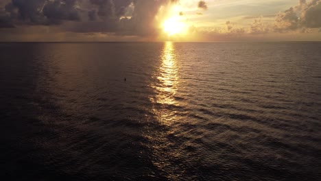 un pintoresco amanecer o atardecer sobre el océano con vistas al horizonte desde un dron aéreo que vuela hacia la luz del sol