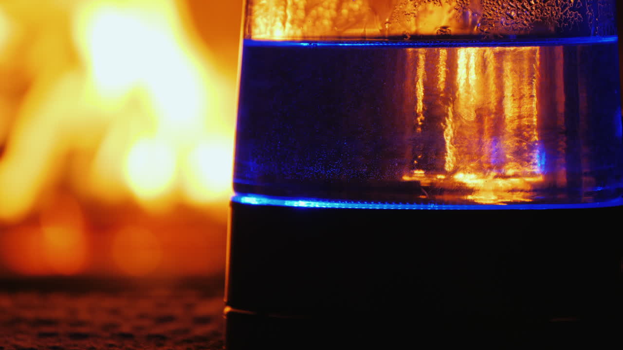 el agua hierve en un hervidor eléctrico retroiluminado un fuego en el fondo arde en el fondo