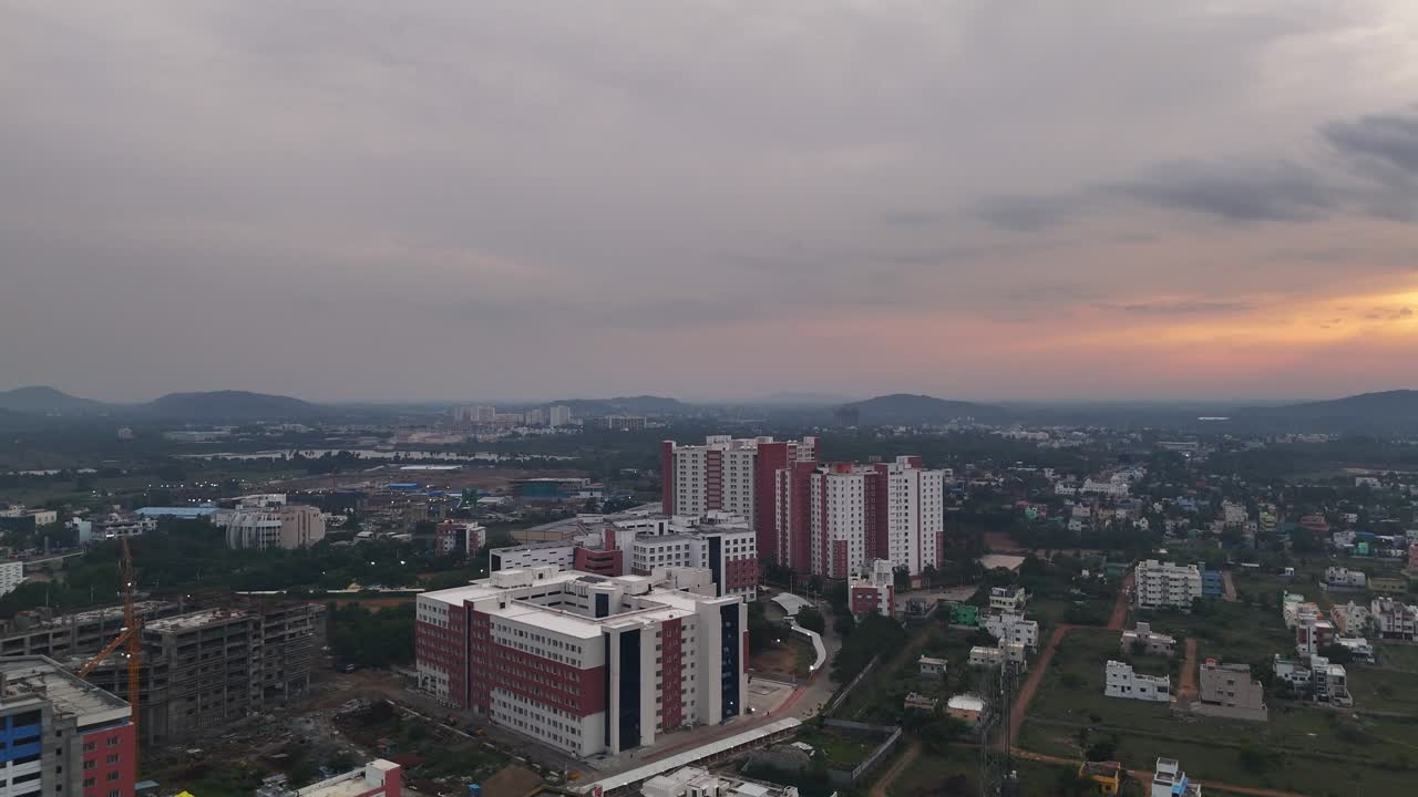 Filmato da Kelambakkam-Vandalur Rd di una nuova comunità di grattacieli. Edifici con esterni rossi e bianchi e pannelli solari sui tetti, che simboleggiano una vita urbana moderna e sostenibile in una città in crescita