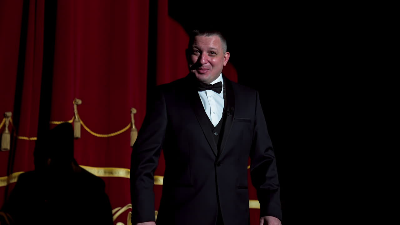 Actor on a stage. Adult man talks to the public in microphone or sings songs. Theater concept.