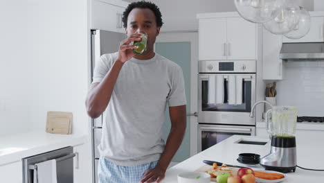 portrait of man wearing pyjamas in kitchen drinking freshly made  fruit and vegetable smoothie