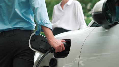 hombre de negocios y mujer de negocios utilizan una estación de carga progresiva para el coche eléctrico.