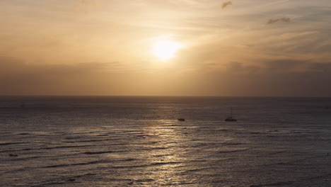 Hora-Dorada-Del-Atardecer-Bajo-En-La-Bahía-De-Waikiki,-Barcos-En-El-Horizonte-En-Medio-De-Las-Olas-Del-Océano,-Hawaii