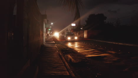 Walking-on-sidewalk-and-big-truck,-cars-and-scooters-driving-on-street-at-night.-Pedestrian-point-of-view.-Valladolid,-Mexico