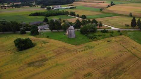 aerial shot of an old windmill in the field by the road, zoom out