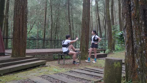 asian couple taking photo with smartphone during outdoor trail run in indonesian forest