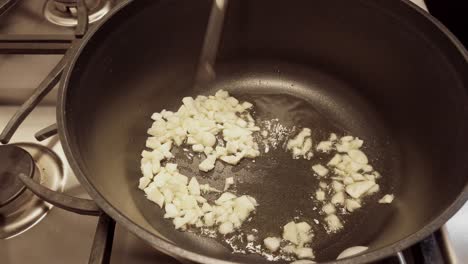 no person, non-stick pan adding chopped garlic to olive oil, side profile shot.