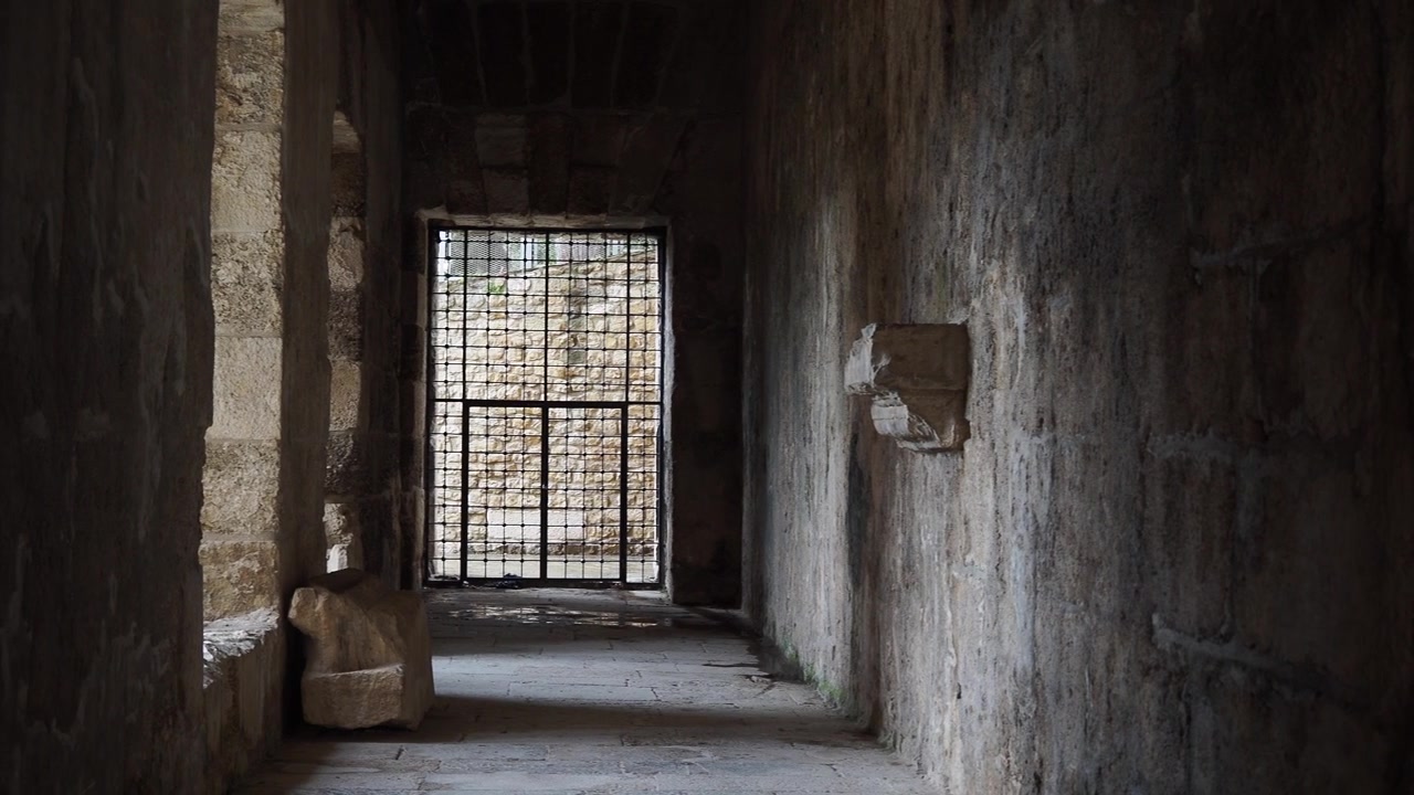 Antico corridoio in pietra che conduce a un cancello di metallo