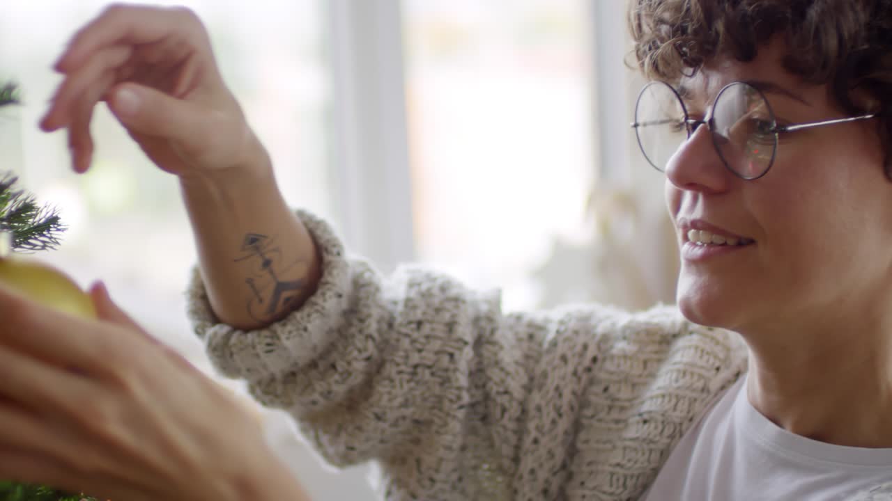mujer con gafas decorando el árbol de navidad